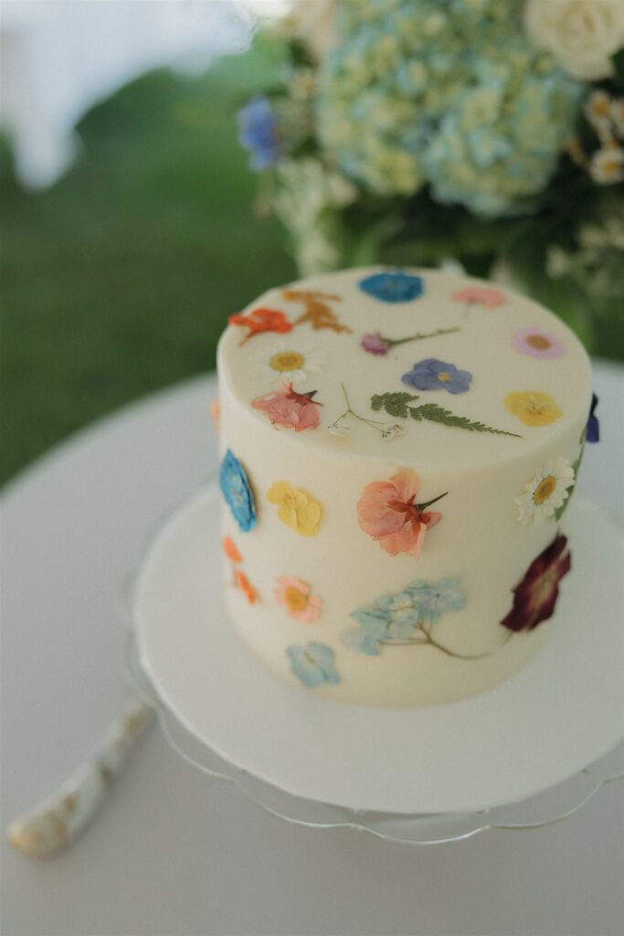 Simple white wedding cake adorned with pressed edible flowers