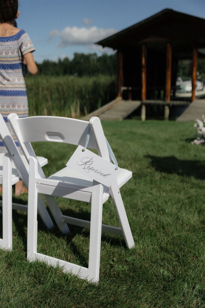 Reserved sign draped over white chair of wedding guests