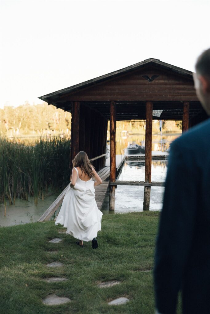 Bride walks towards the boat dock as groom trails along behind her