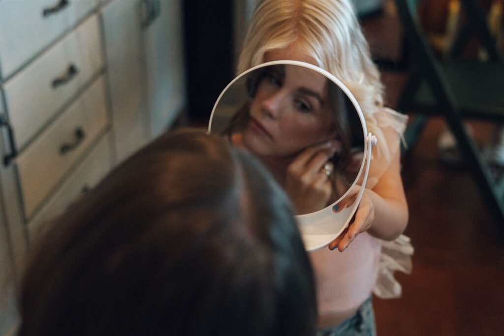 Flower girl holds mirror for the bride to put on her earrings