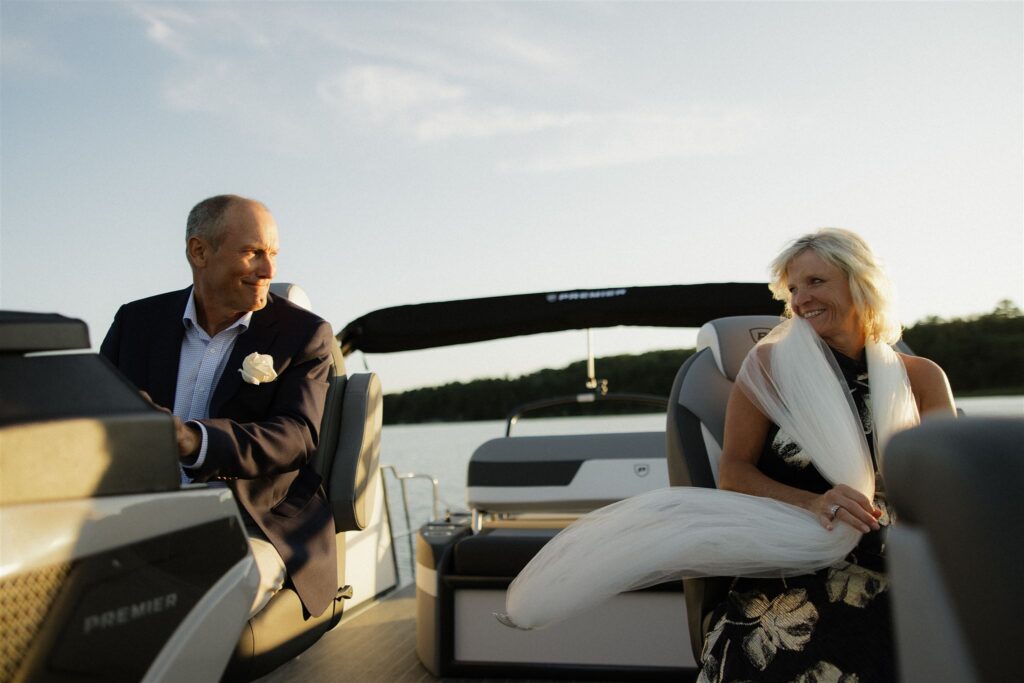 Parents of the groom smile at each other as they drive newlyweds around on sunset cruise