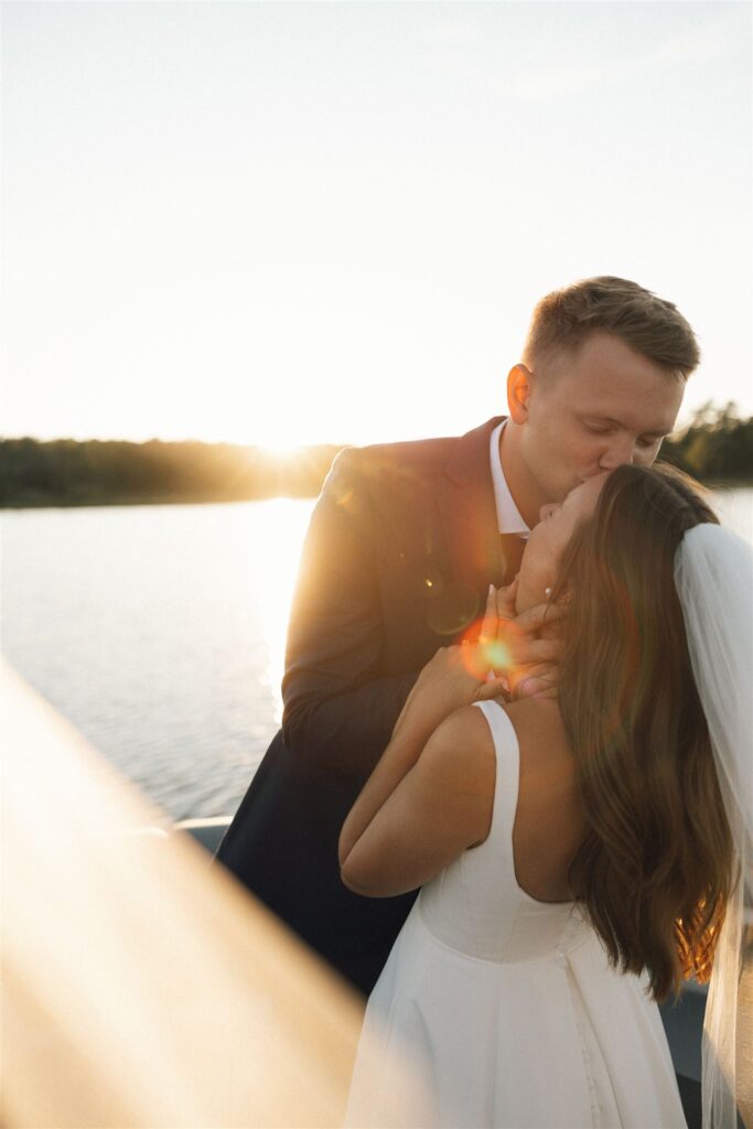 Groom kisses bride's forehead as they embark on a sunset cruise