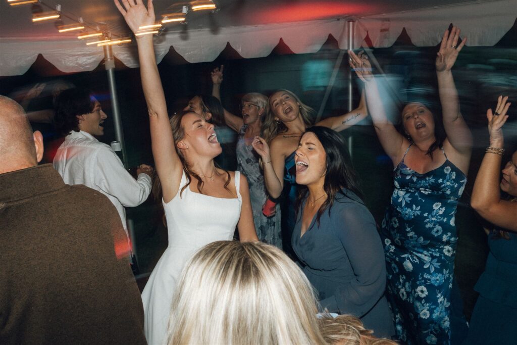 Bride and her friends raise their hands in the air as they dance the night away