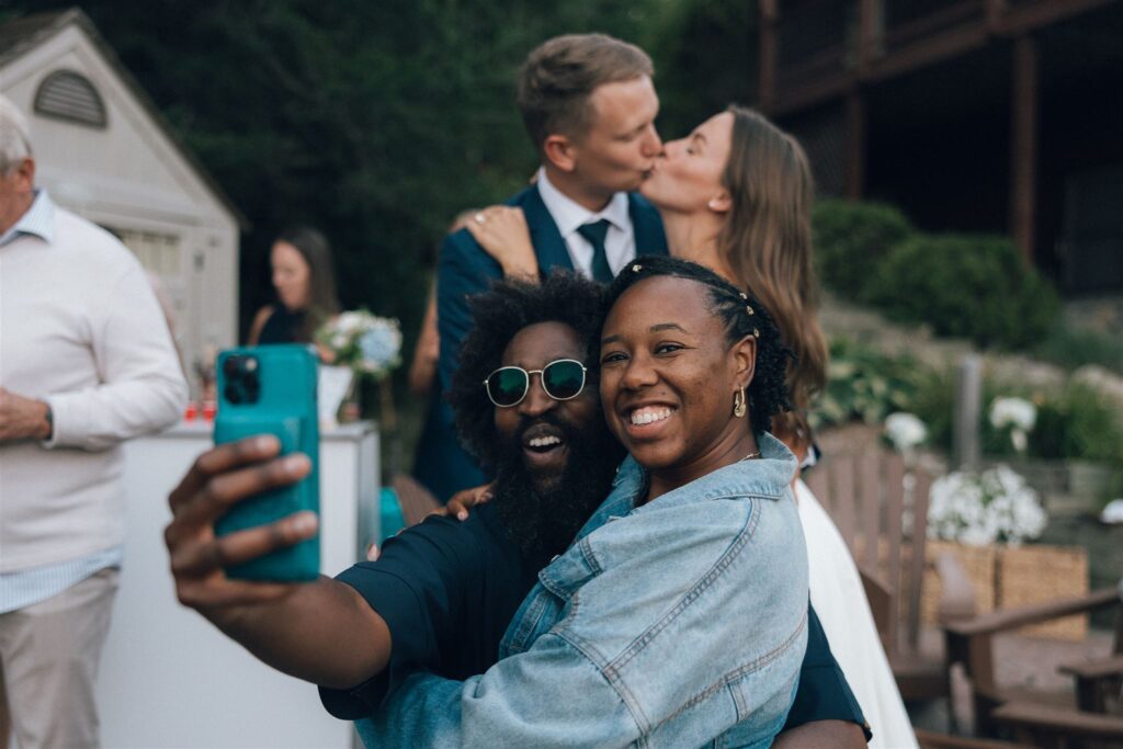 DJ Obie takes a selfie with newlyweds kissing in the background