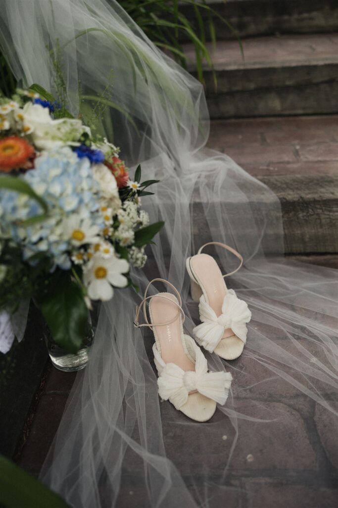 Bride's shoes, veil, and bouquet sit on the steps of the cabin