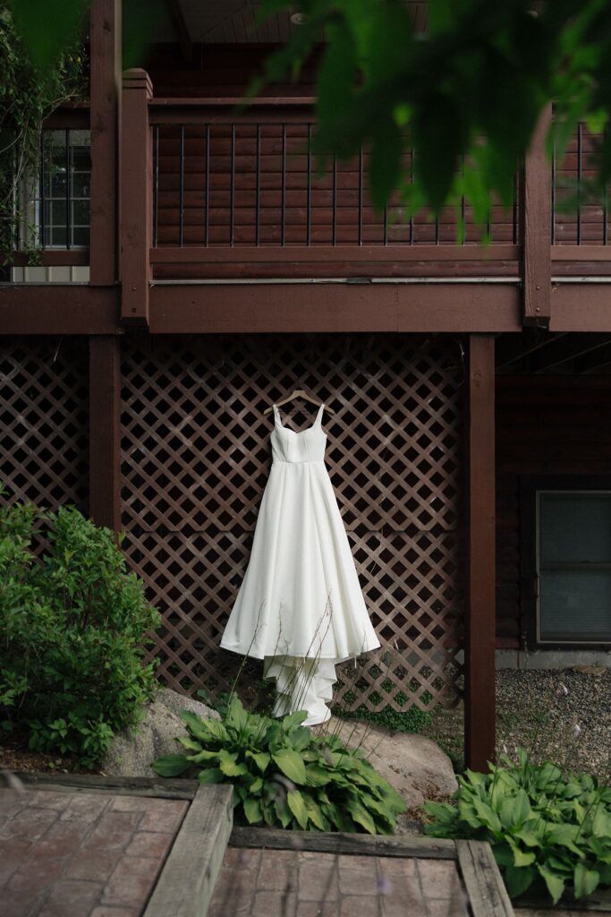 Bride's wedding gown hangs on the latticed wood of their cabin