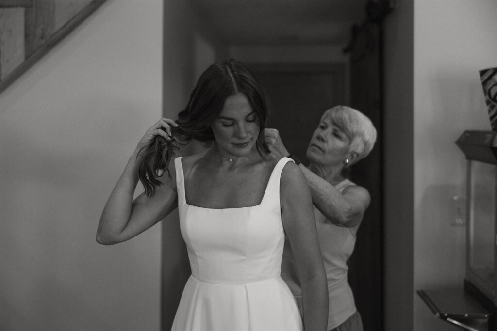 Mother of the bride clasps bride's necklace as she holds her hair up to make room