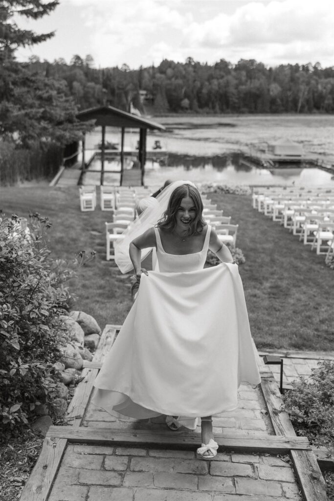 Bride holds her dress up as she makes her way up the steps of the cabin with Lake Leech behind her