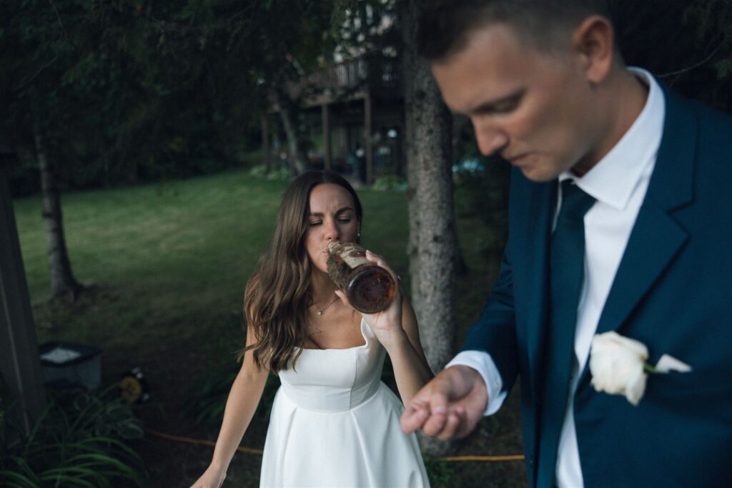 Bride drinks straight from a bottle of Four Roses bourbon in 'bury the bourbon' wedding tradition