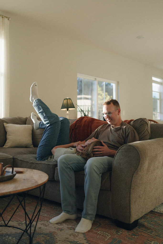 Man holds woman's head as she lays in his lap on the couch