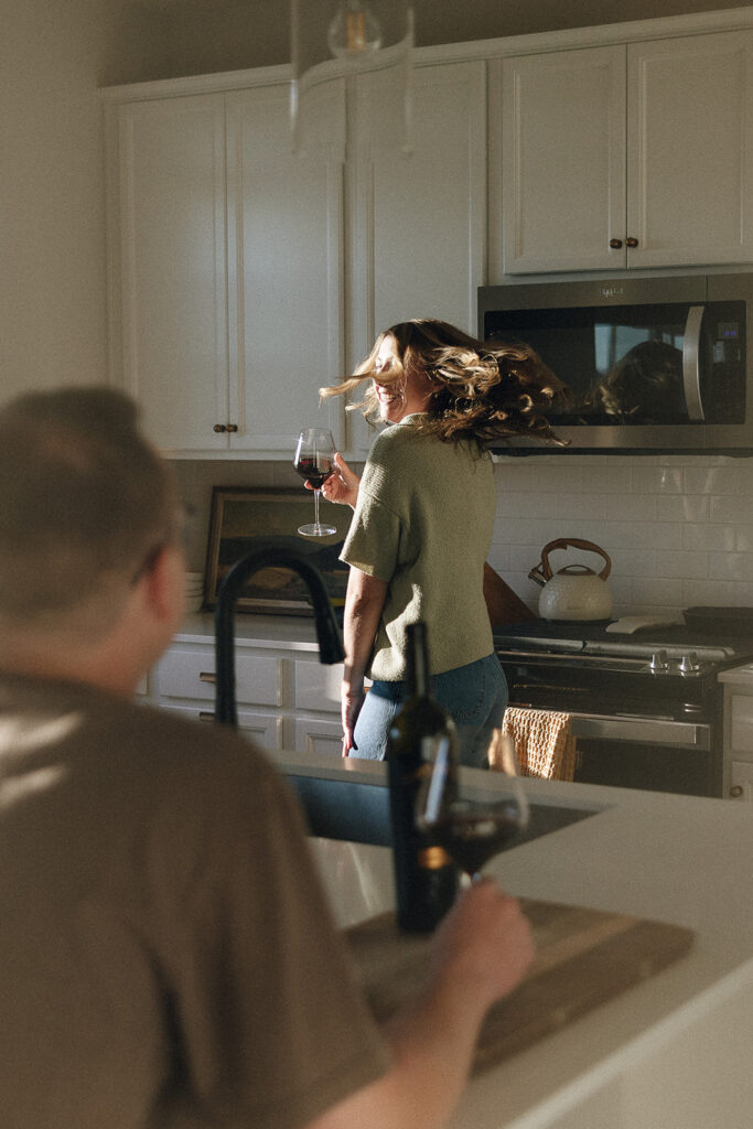 Woman twirls around kitchen while husband watches