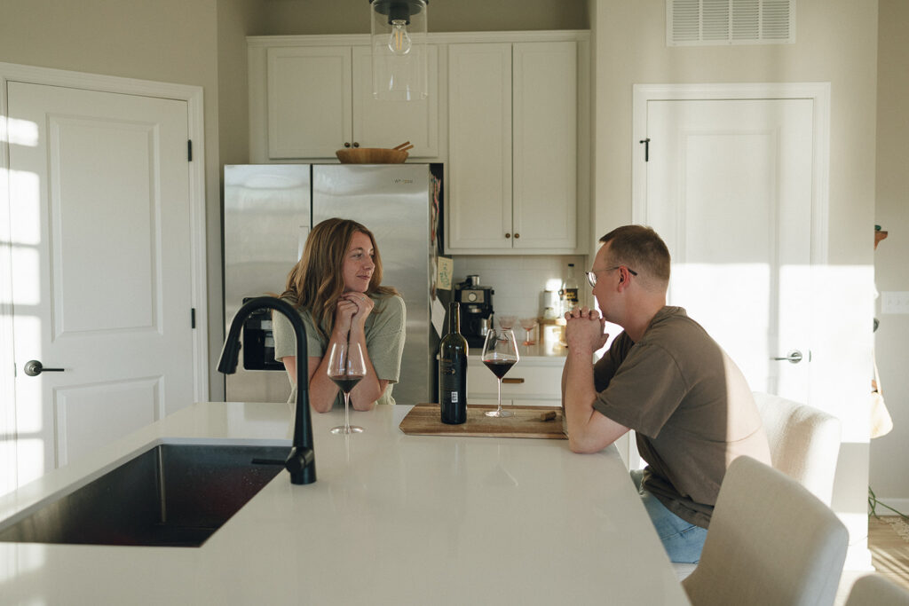 Married couple enjoys a glass of red wine at their kitchen island