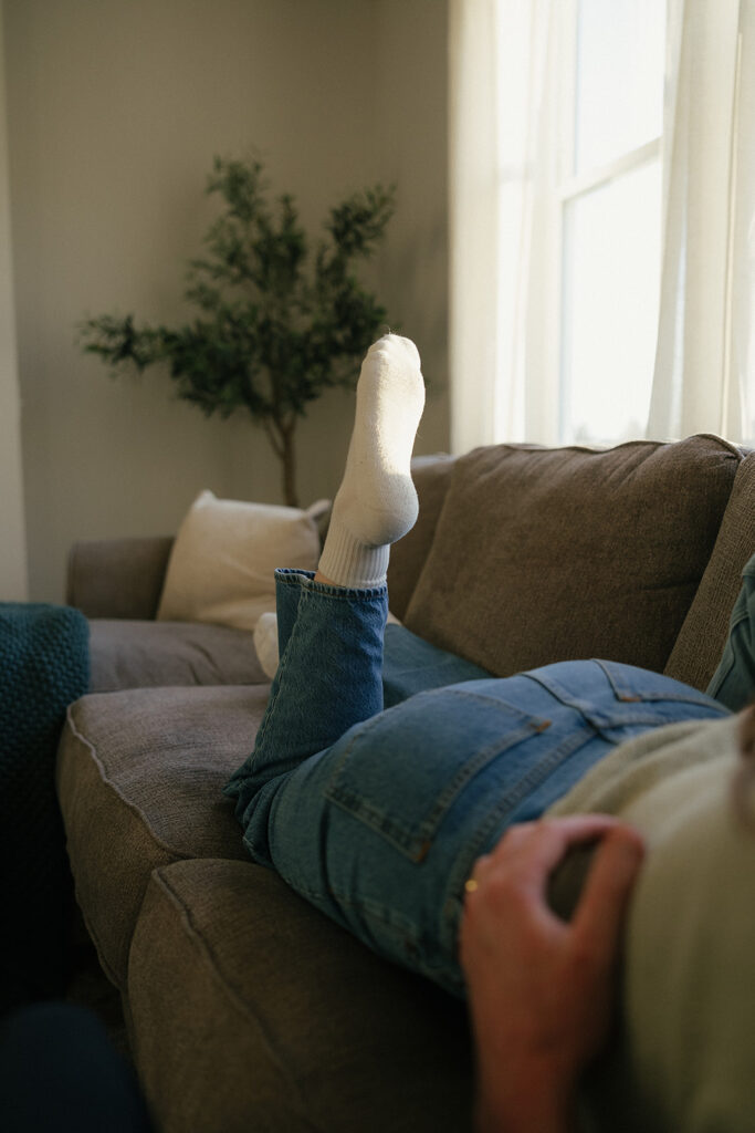 Woman wearing white tube socks lays on couch with her feet in the air