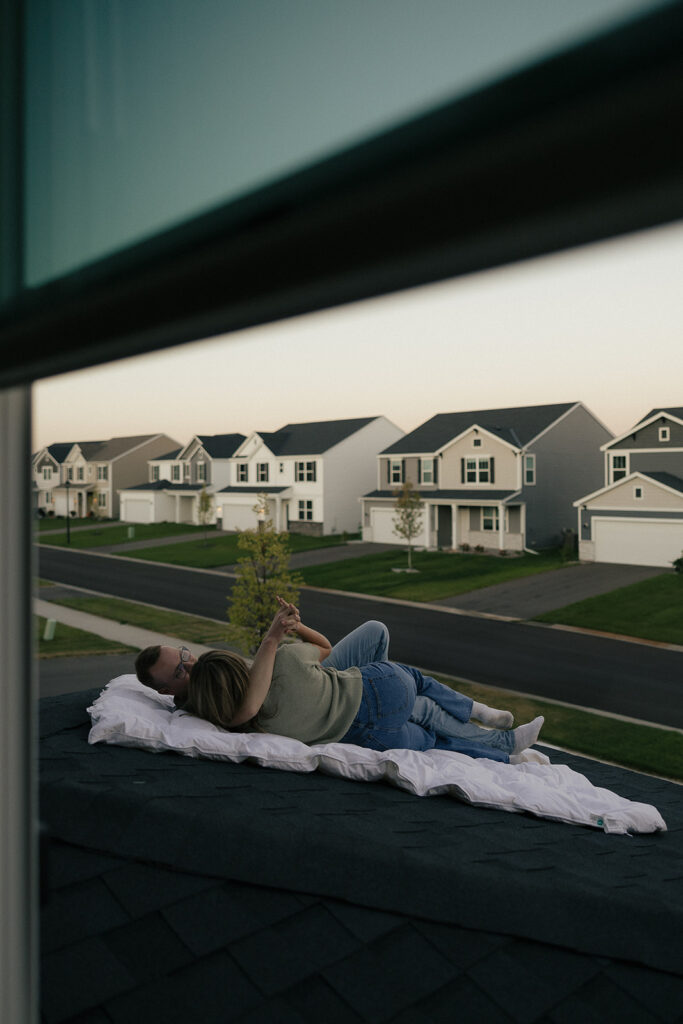 Couple lays on white duvet on the roof of their Minnesota home