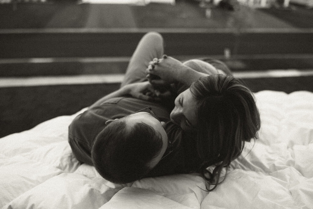 Minnesota couples photography of man and woman snuggling on white duvet on roof of their home