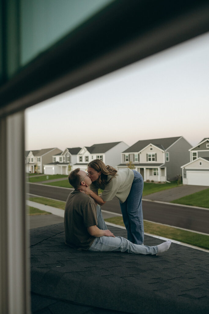 Woman leans down to kiss her husband on the rooftop of their Minnesota home