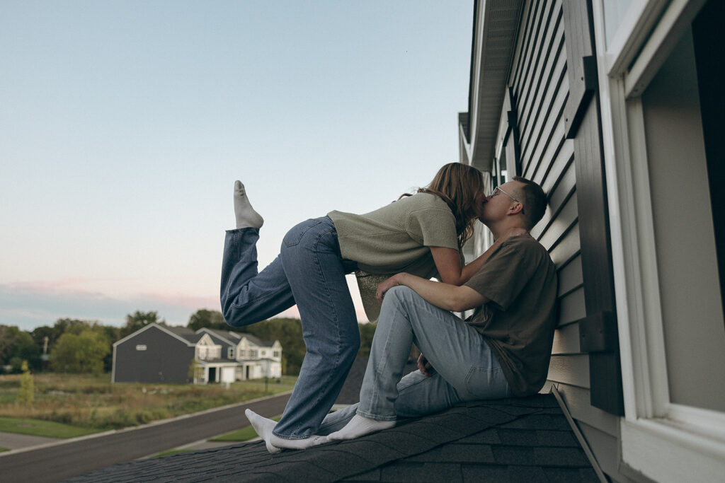 Woman pops her sock-clad foot in the air as she leans down to kiss her husband