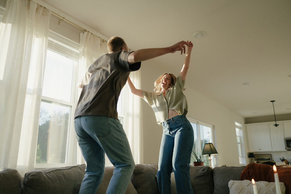 Couple jumps jubilantly on living room couch