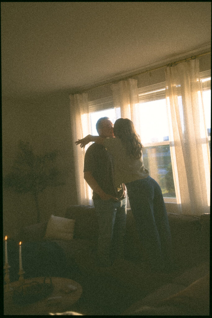 Woman leans in to kiss her husband in the glow of sunset