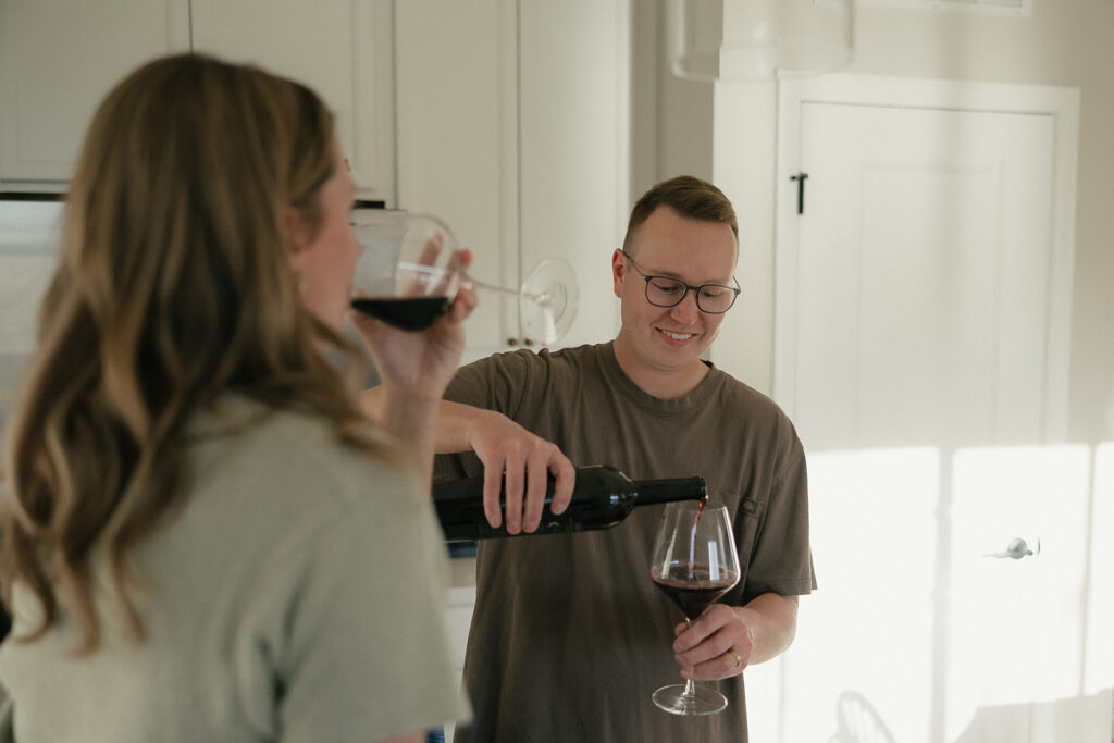 Husband pours himself a glass of wine while his wife takes a sip from her glass