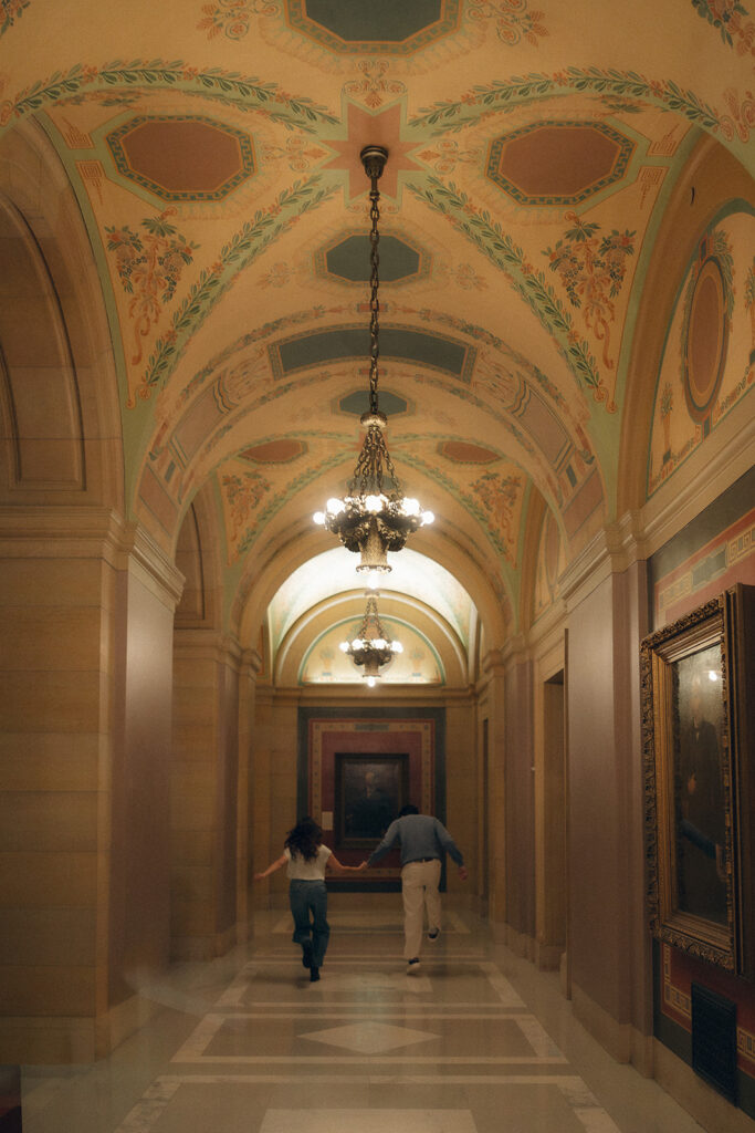 Silhouette of couple running hand-in-hand through marble hallway