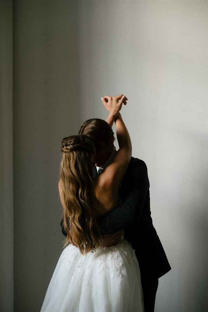 Bride drapes her arms romantically around groom's neck