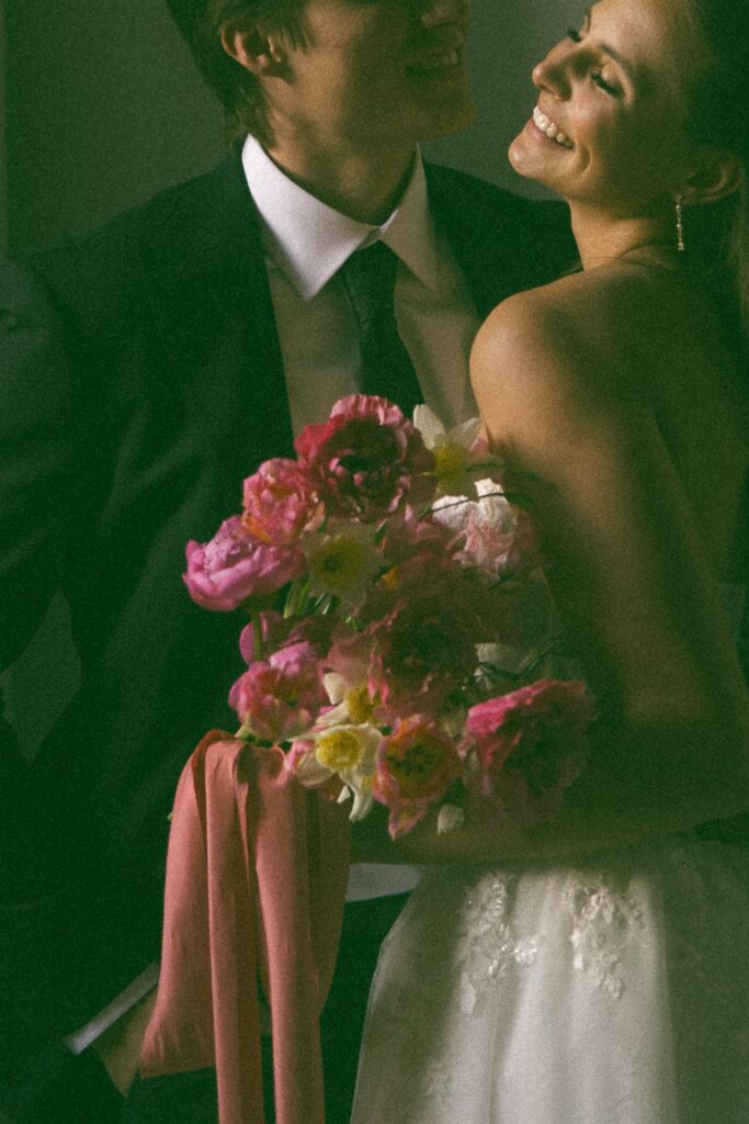 Bride throws her head back in laughter as groom tells her a secret