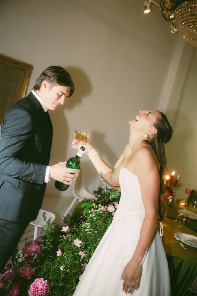 Bride laughs while groom pours her whiskey