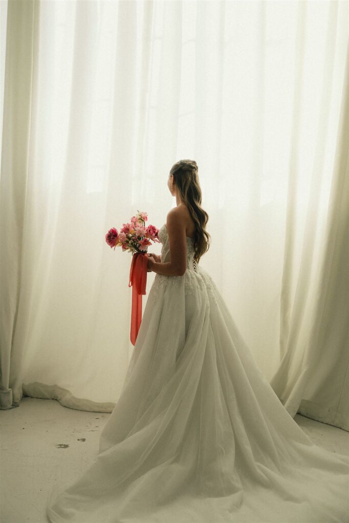 Bride stands in the glow of natural daylight