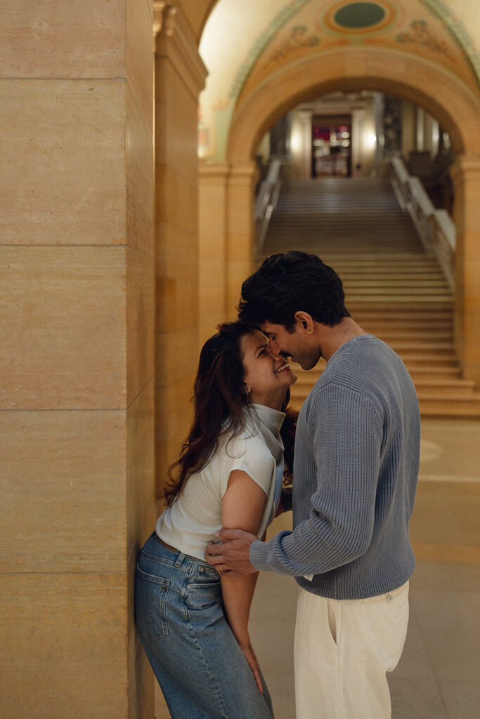 Candid cuddle in marble archway—one of many film-like engagement images