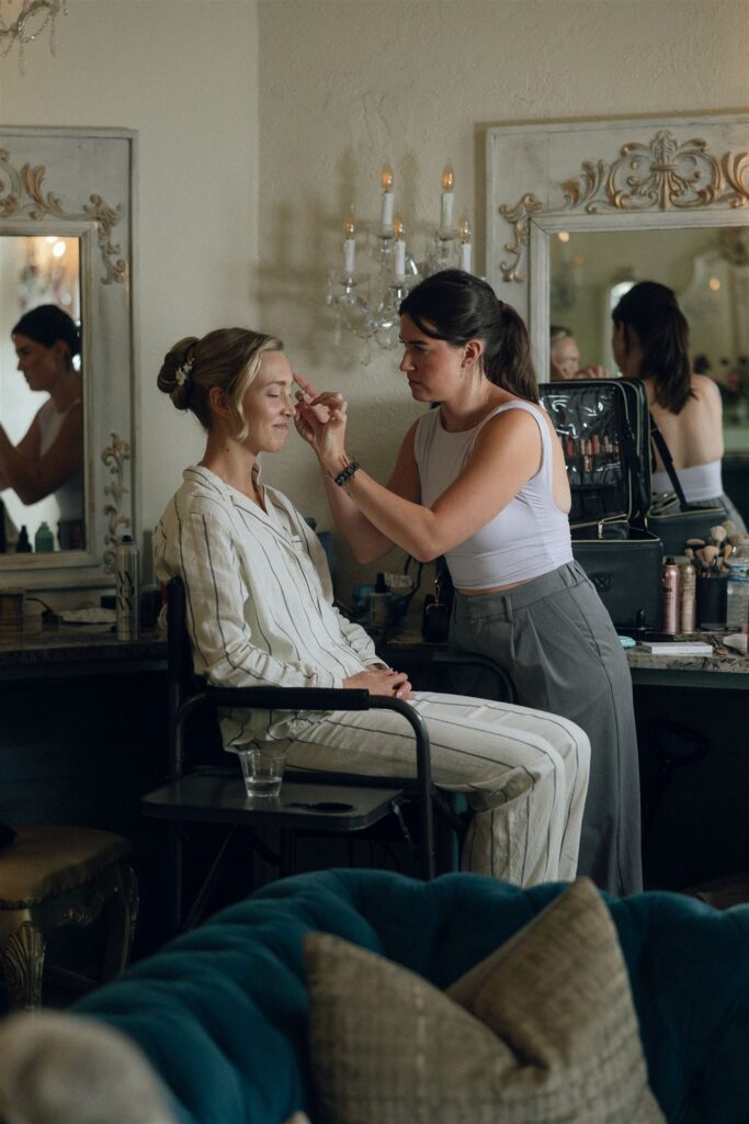 Kaylyn getting her makeup done in a cozy, light-filled corner of Edward Anne Estate’s bridal suite