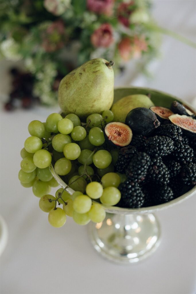 Dutch-inspired still life fruit bowl with grapes and figs on reception table.