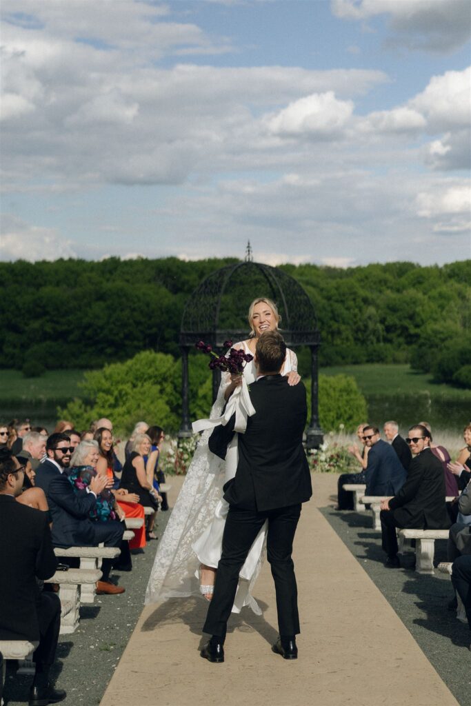 Joyful recessional moment with bride and groom dancing down the aisle.