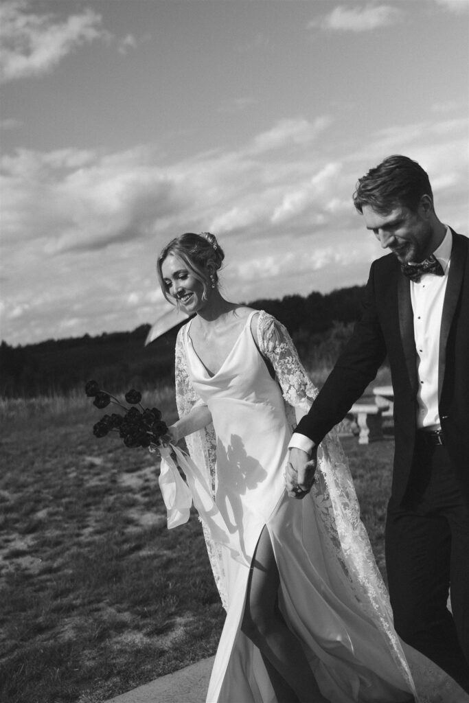 Bride and groom strolling through Edward Anne Estate’s grassy landscape post-ceremony.