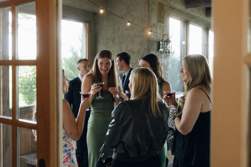 Group of friends laughing with drinks during cocktail hour at Edward Anne Estate.