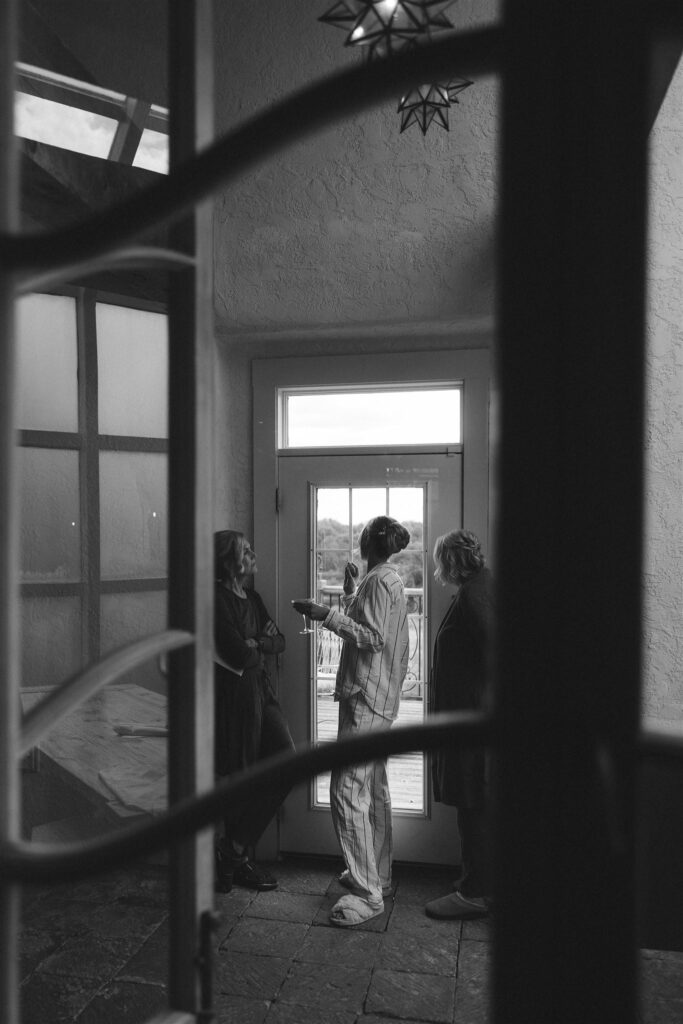 Bride stepping outside in her pajamas while sunlight pours through the door
