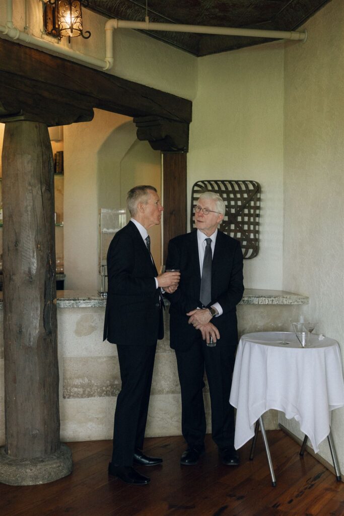 Fathers of the couple chatting near stone pillars inside Edward Anne Estate cocktail hour