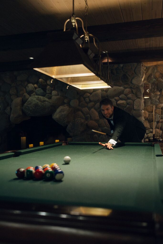 Groom lining up a shot on the pool table in Edward Anne Estate’s billiards room.