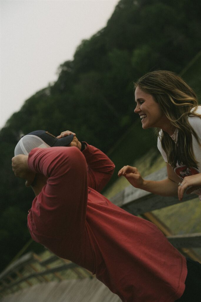 Woman leaning toward man and smiling while he lifts her up on the sand.