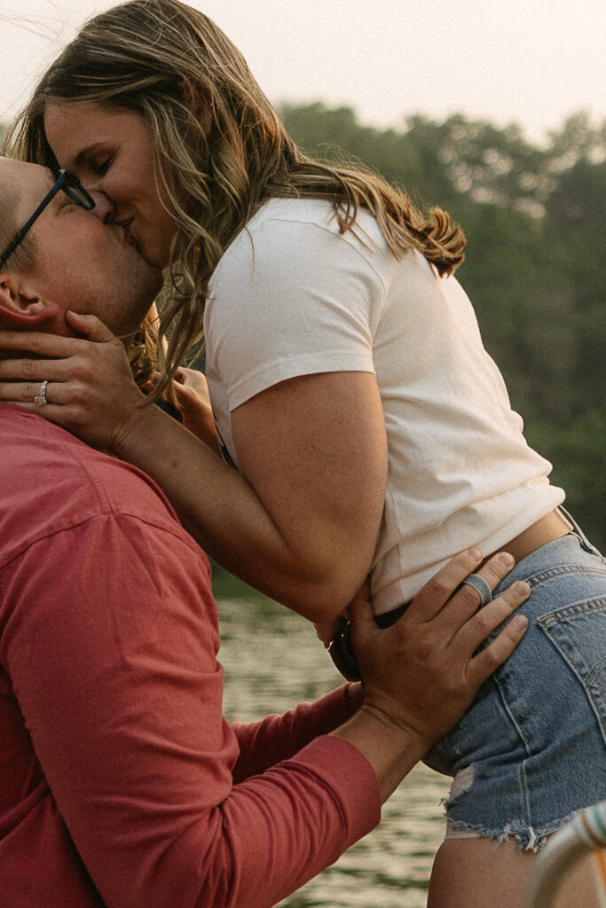 Man and woman embracing and kissing on the beach, her hand resting on his neck.