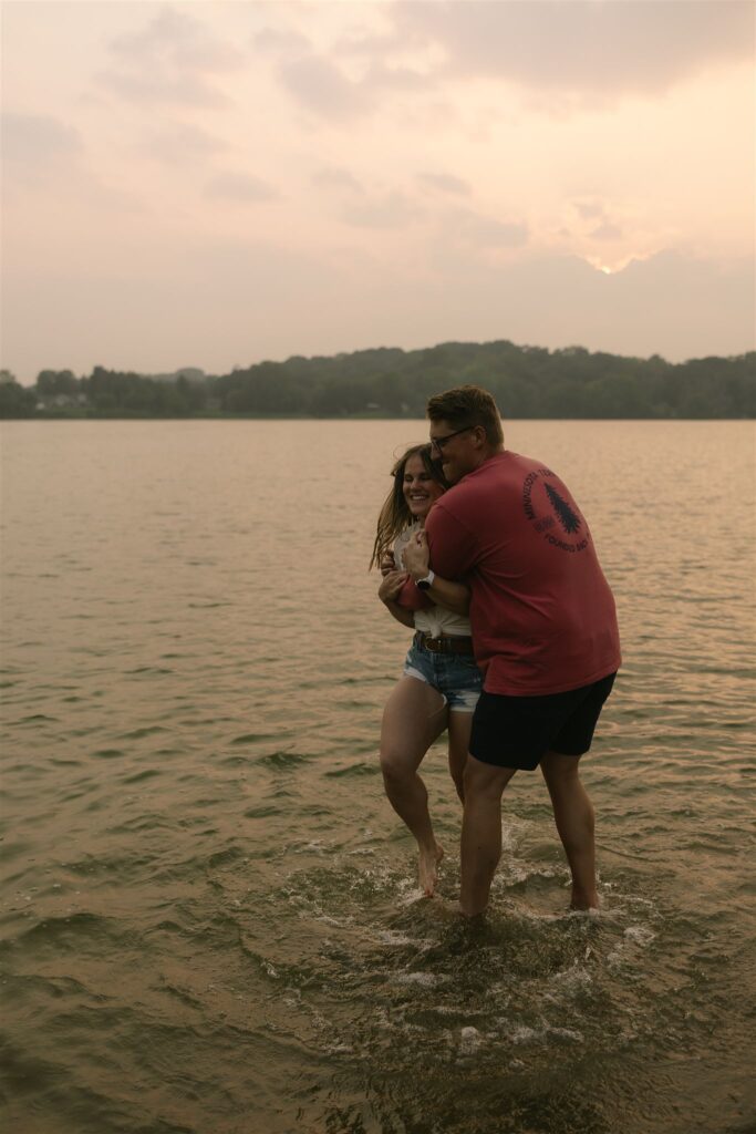 Man grabbing woman around the waist while twirling in Minnesota summer engagement photos.