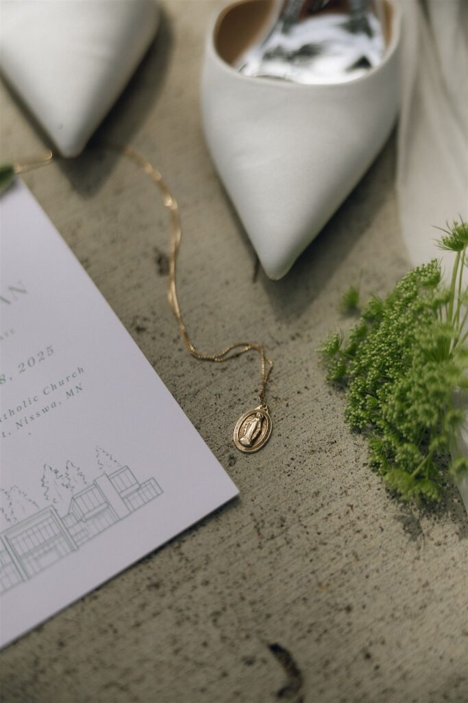 Gold locket and bridal shoes styled with the wedding invitation suite.