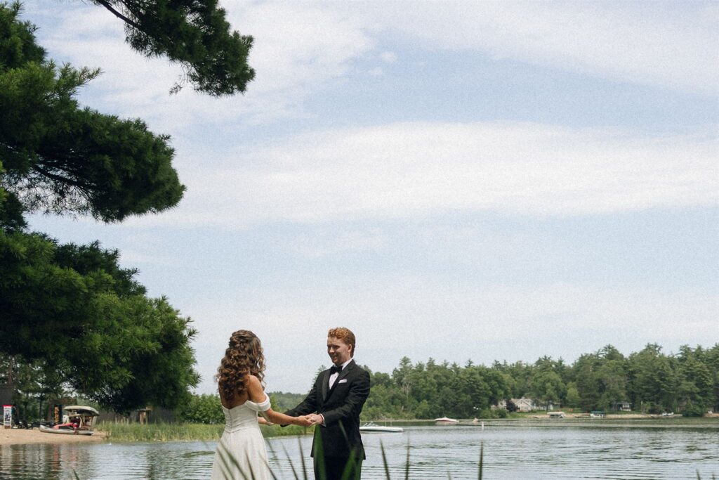 Bride and groom holding hands by Clark Lake in candid wedding photography.