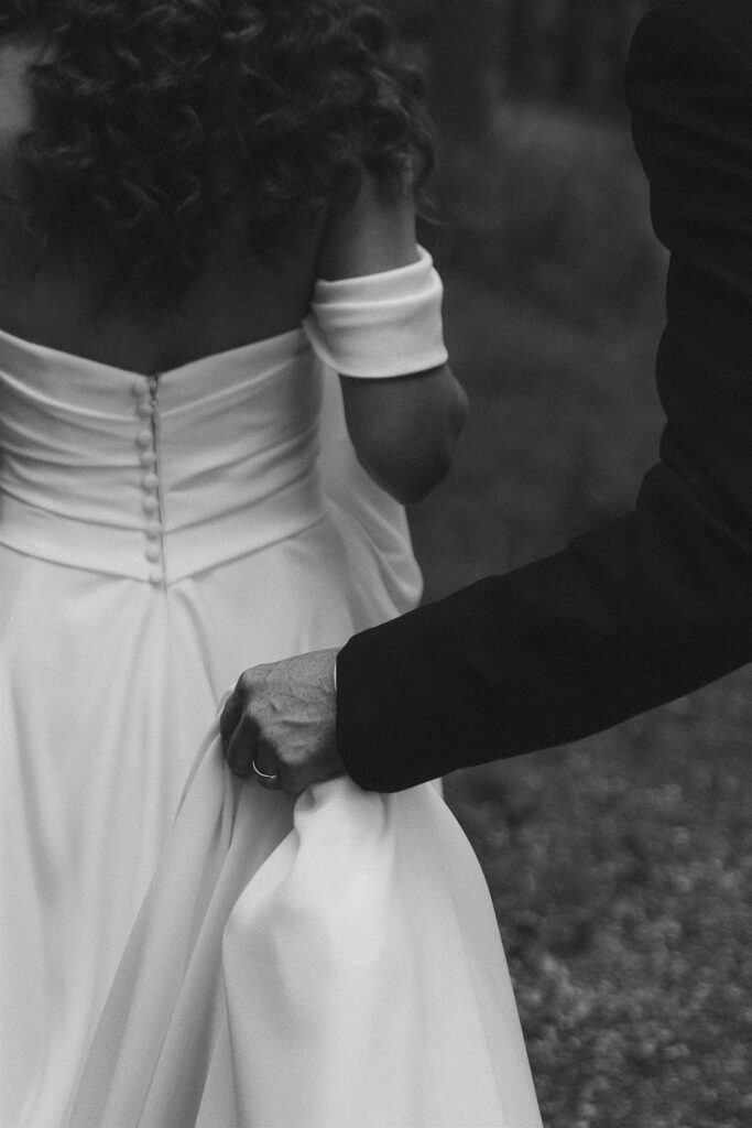 Groom adjusting the bride’s gown during portraits.