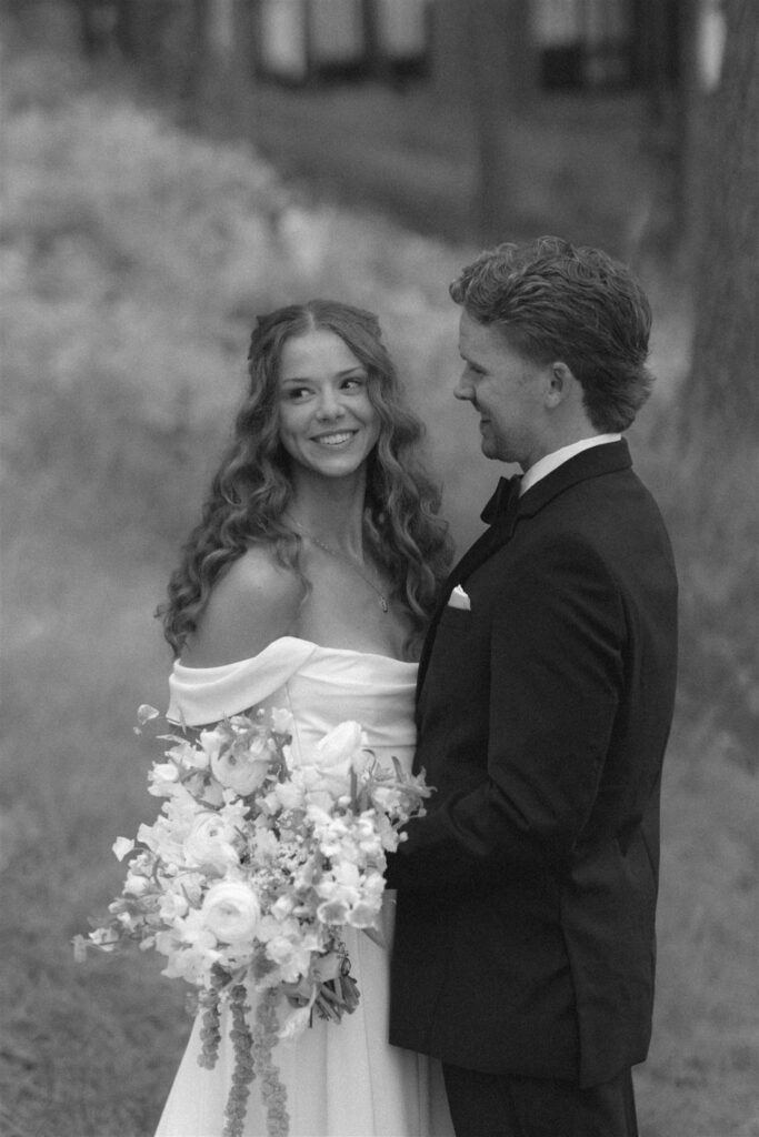 Bride and groom smiling together during portraits outside the Minnesota wedding venue in documentary style wedding photos.