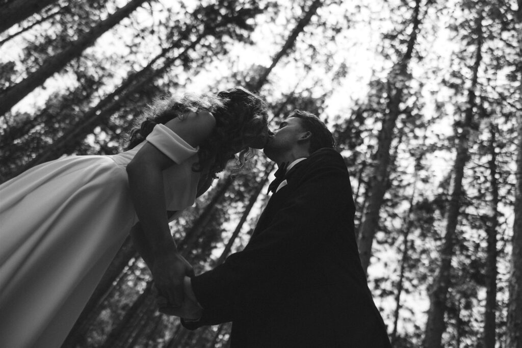 Bride and groom kissing beneath the trees in documentary style wedding photos.