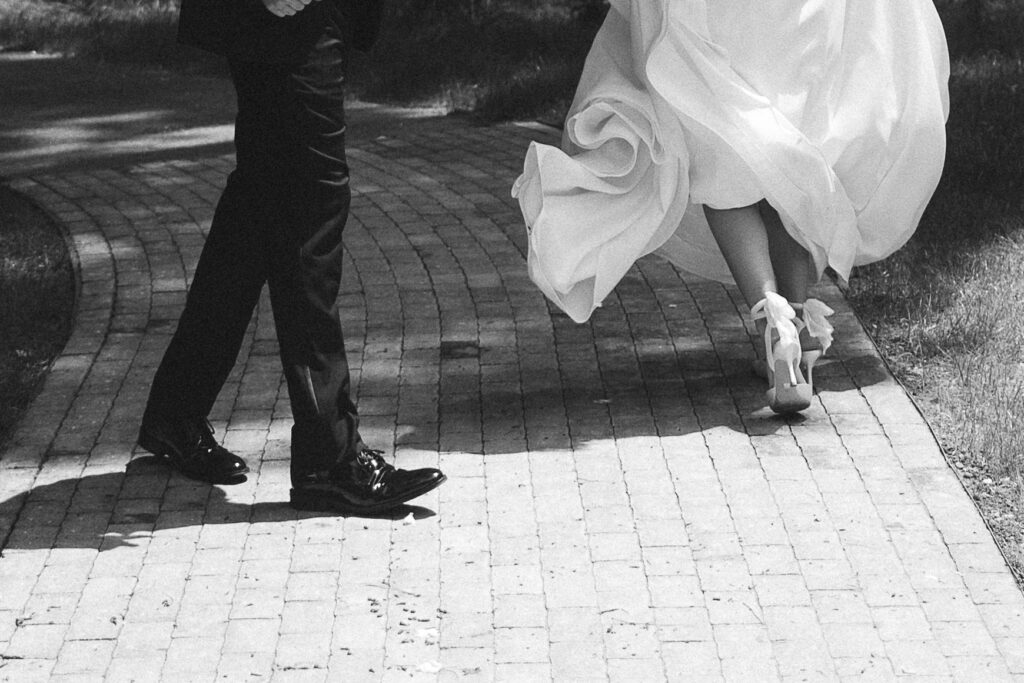 Couple walking together, her dress flowing behind her in documentary style wedding photos.
