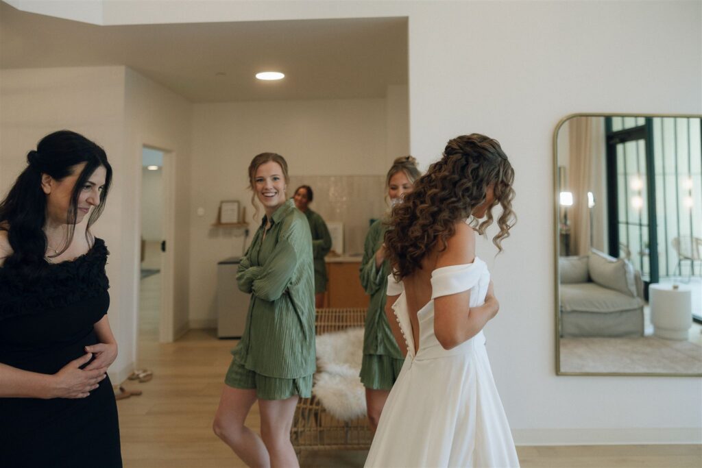 Bride laughing with bridesmaids during candid wedding prep