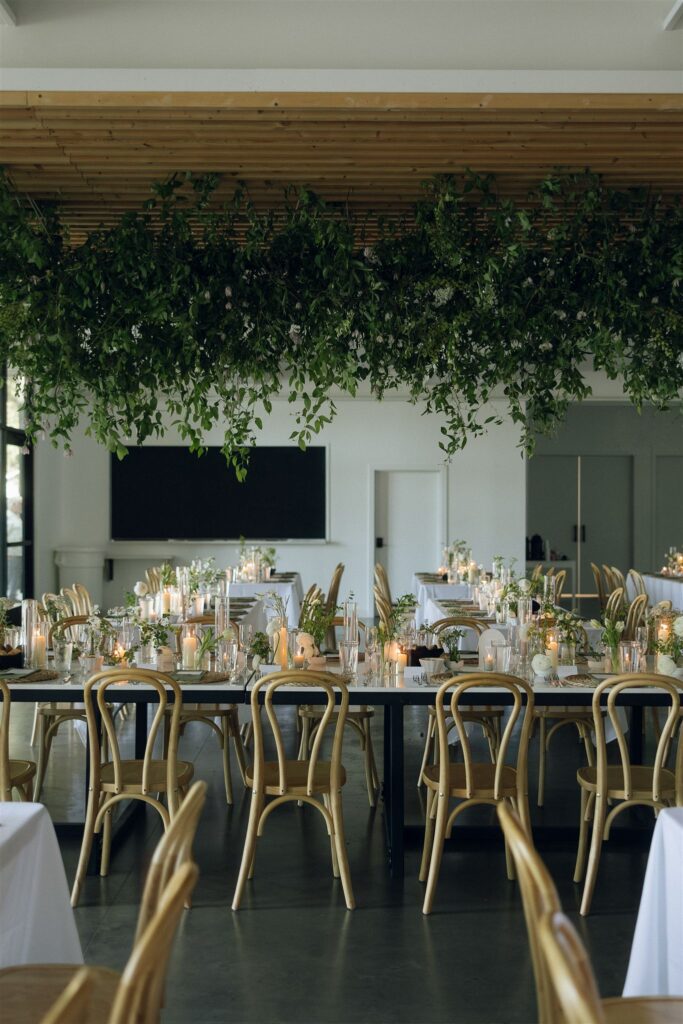 Reception tables set with candles and hanging greenery, captured in candid wedding photography.
