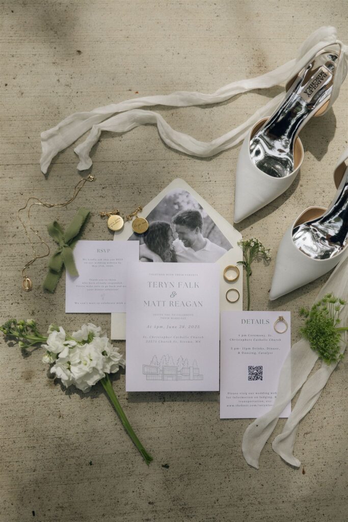 Flatlay of wedding invitation suite, shoes, and florals styled together.